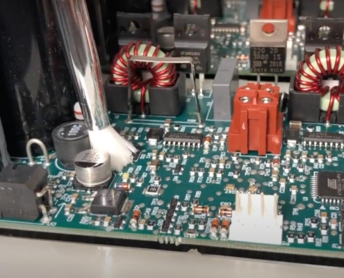 Image of a circuit board being coated with a brush.